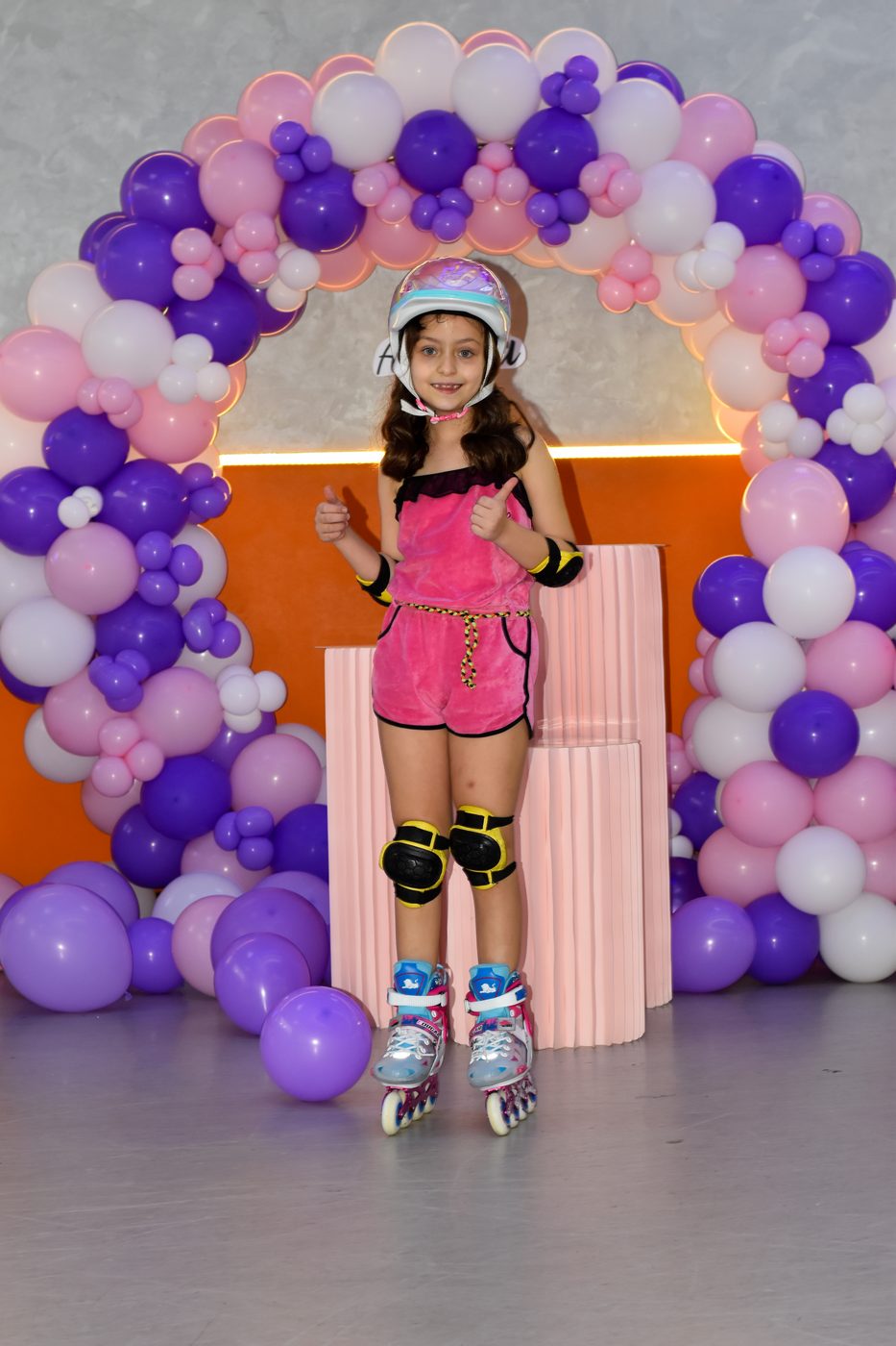 Birthday girl in skates under balloon arch